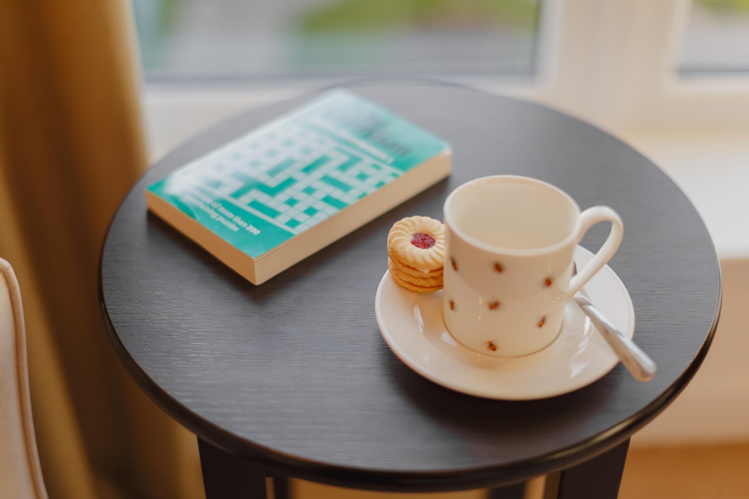 cup of tea and biscuit with a book on a round coffee table