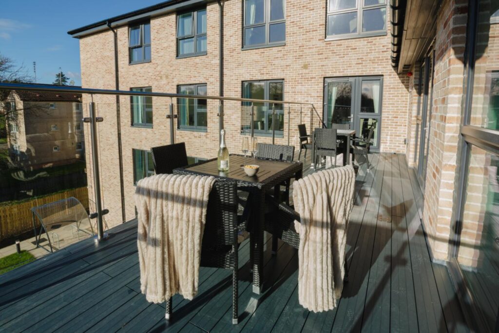 care home balcony in the sun with outdoor table and chairs and champagne