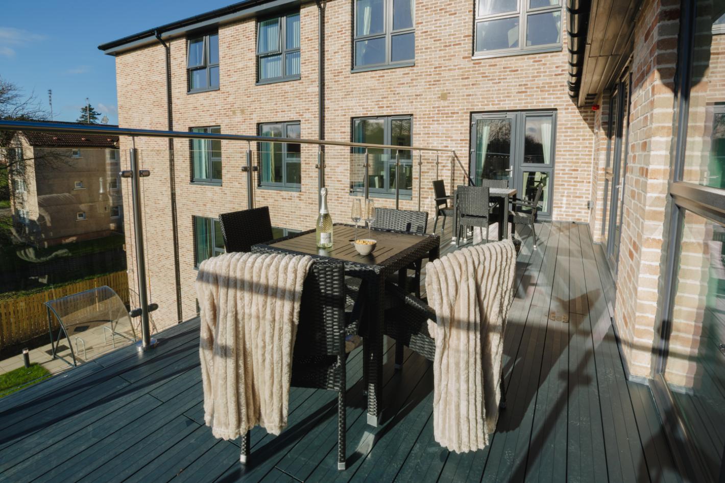 care home balcony in the sun with outdoor table and chairs and champagne