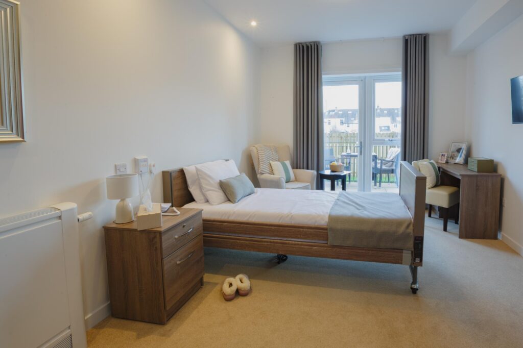 care home bedroom with white walls and wooden furniture