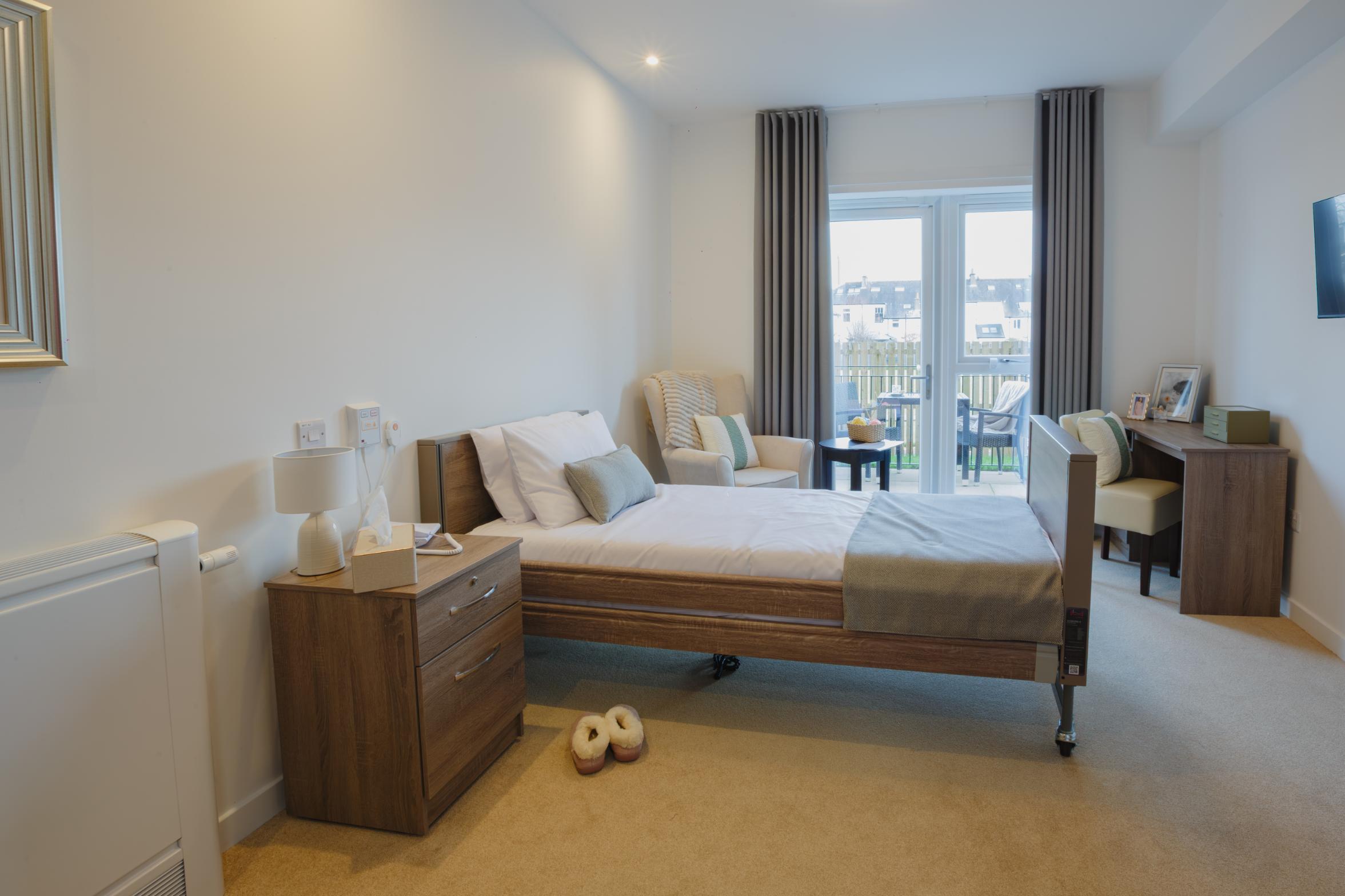care home bedroom with white walls and wooden furniture