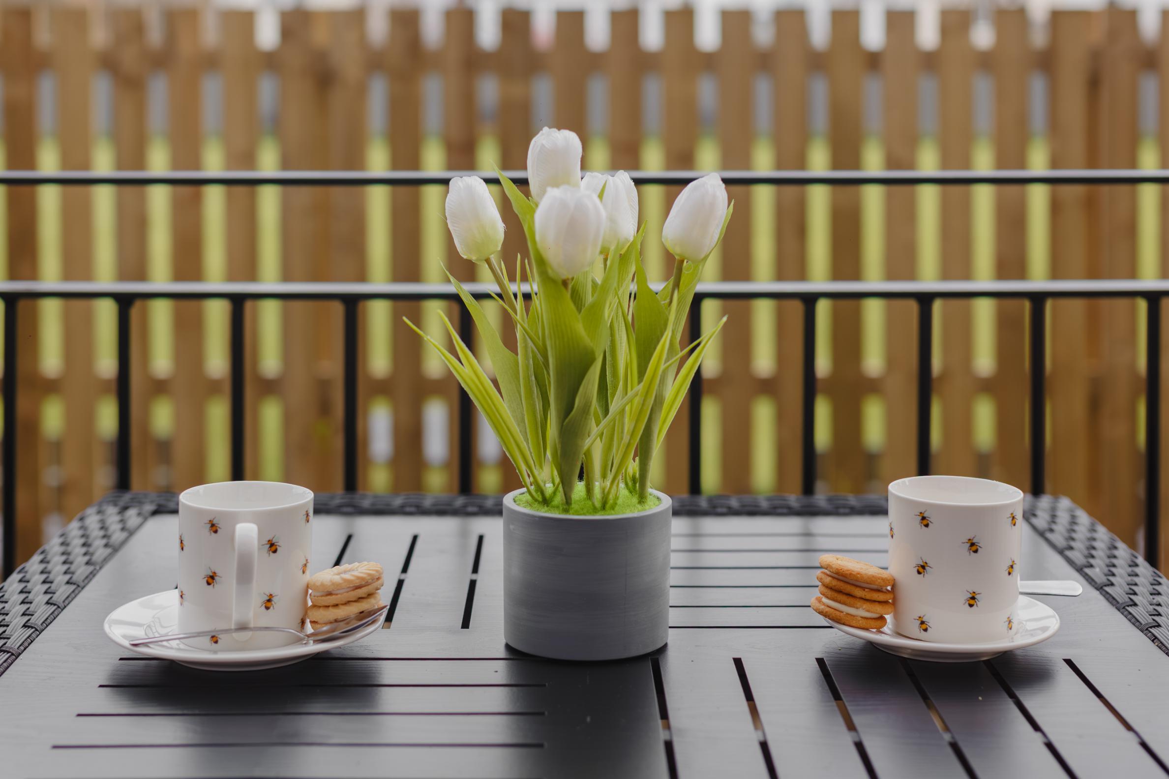 tulips and cups of tea on a balcony table