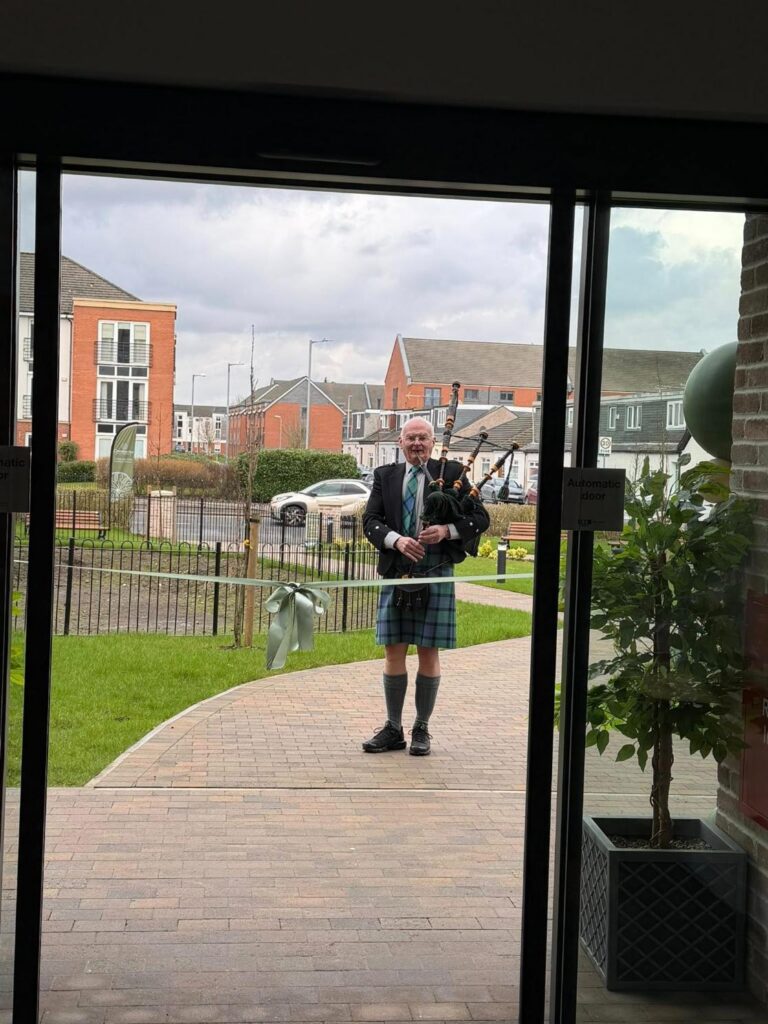 man playing bagpipes at scottish care home opening
