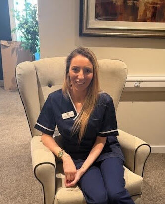 unit manager in dark blue nurses uniform sat in care home chair