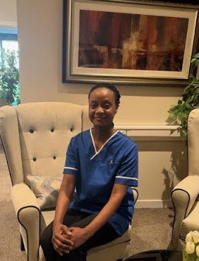 nurse in blue uniform sitting up straight in armchair