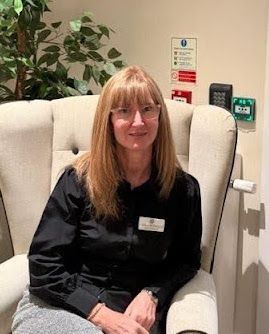 woman with blonde hair smiling and sitting on an armchair