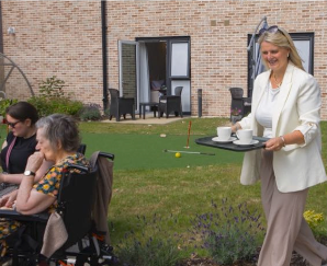 a women carrying a tray of drinks of residents